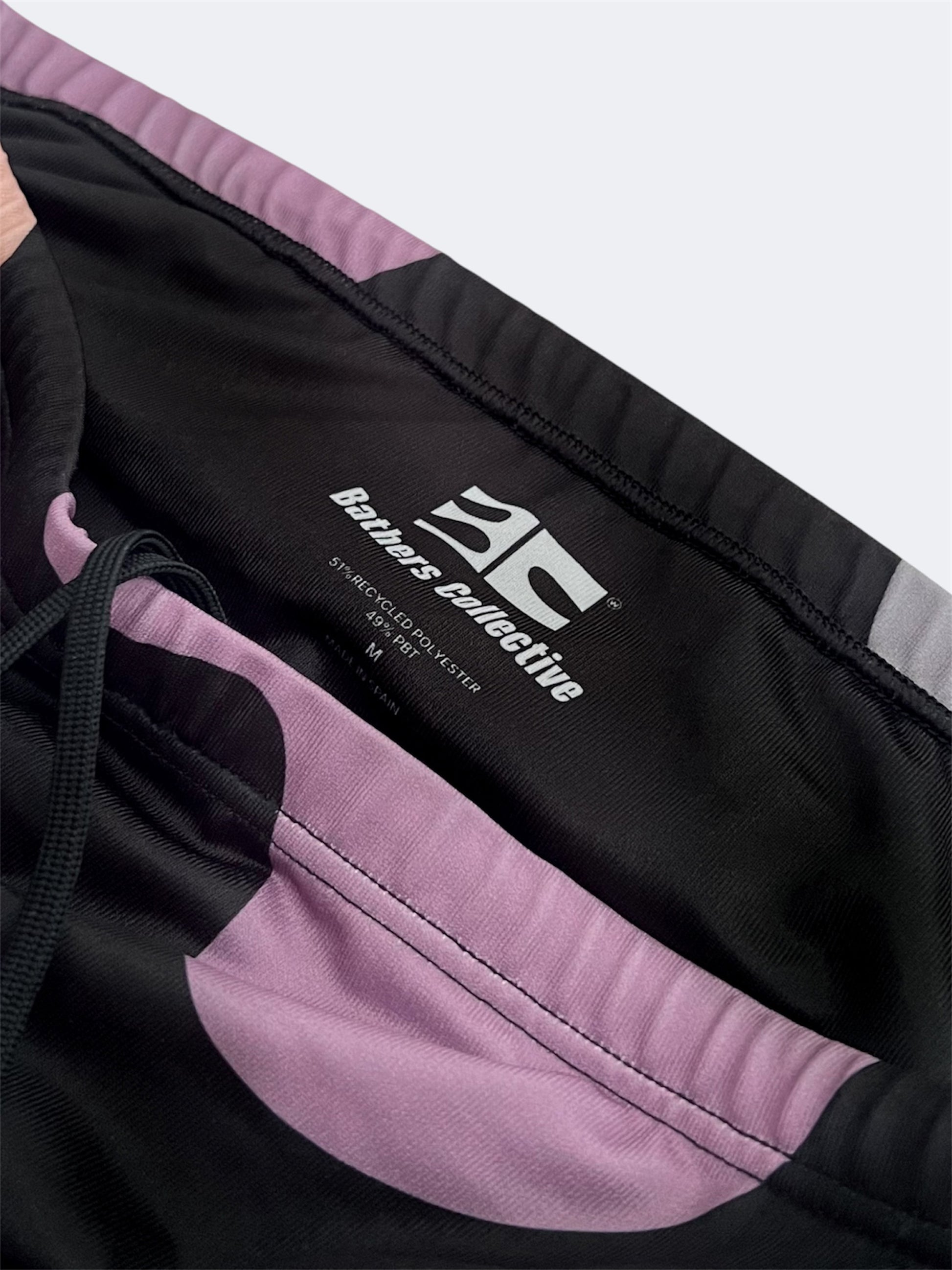 Close up of black and pink swim brief with a brand logo on a white background