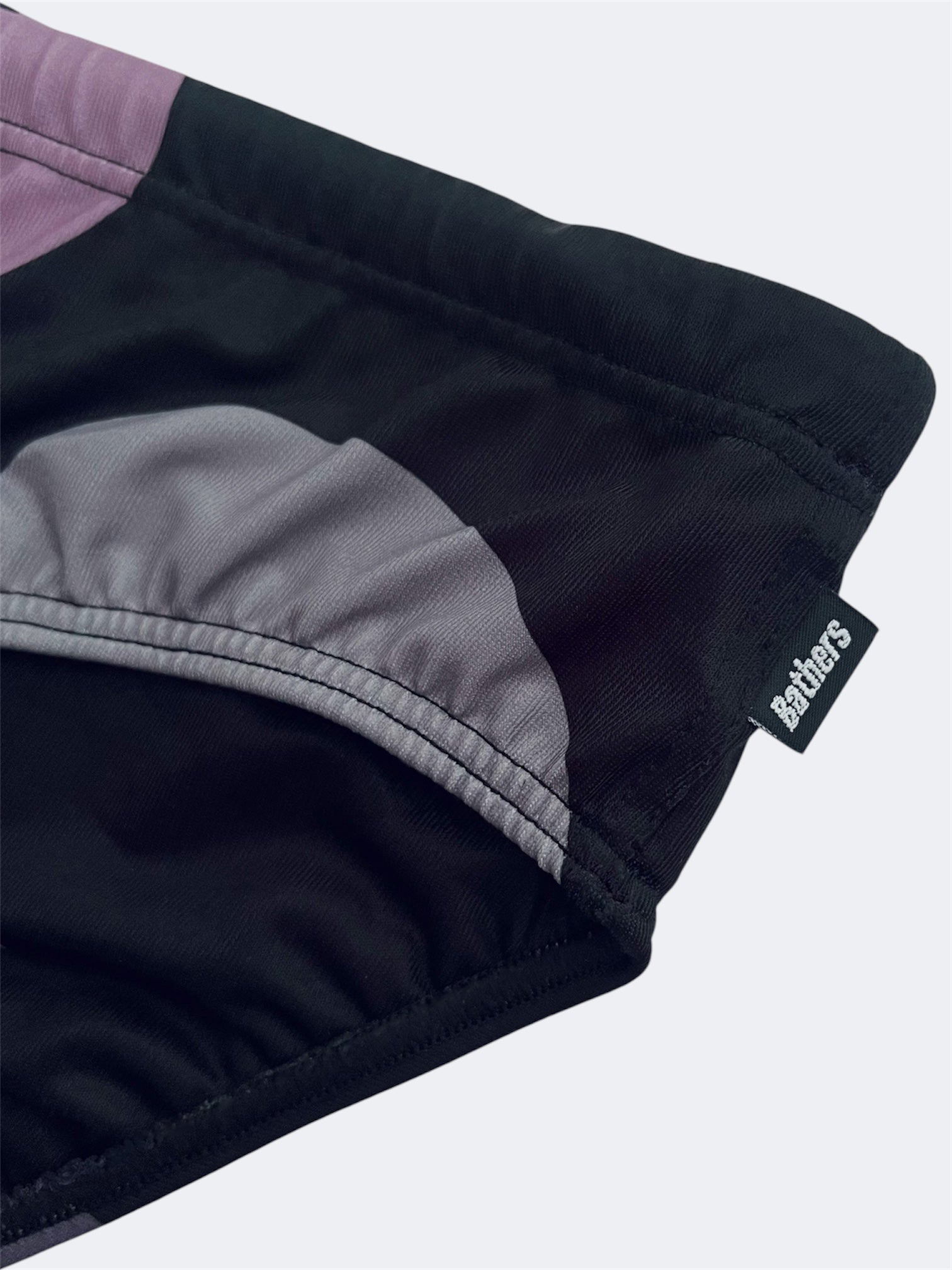 Close-up of black swim brief with logo label in the side seam